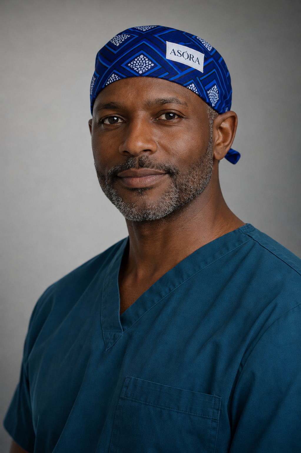 Man wearing a blue scrub top and matching headscarf with 'ASQRA' branding against a gray background