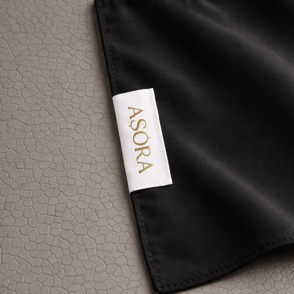ASORA Black Medina-silk scarf, Black fabric with a white label featuring 'ASORA' on a textured gray background