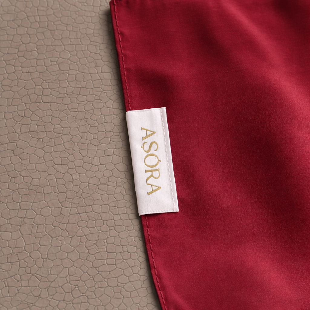 Close-up of a red fabric with an Asora label on a textured beige background
