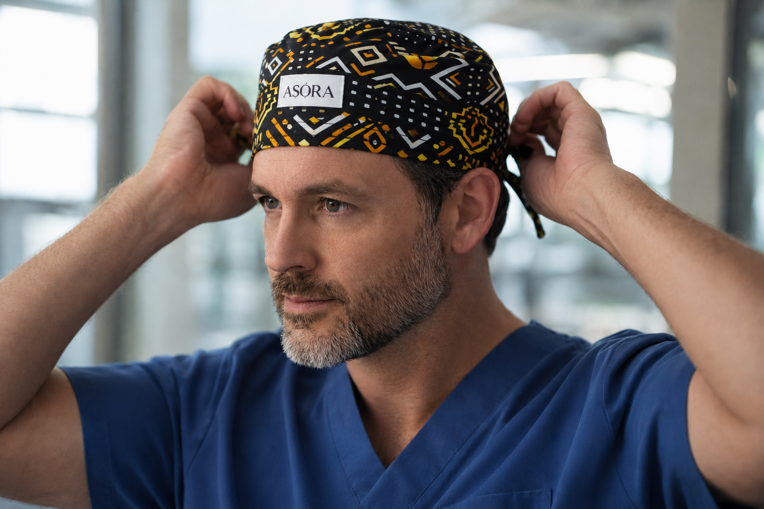 Person wearing a blue scrub top and patterned scrub cap with 'ASORA' branding.