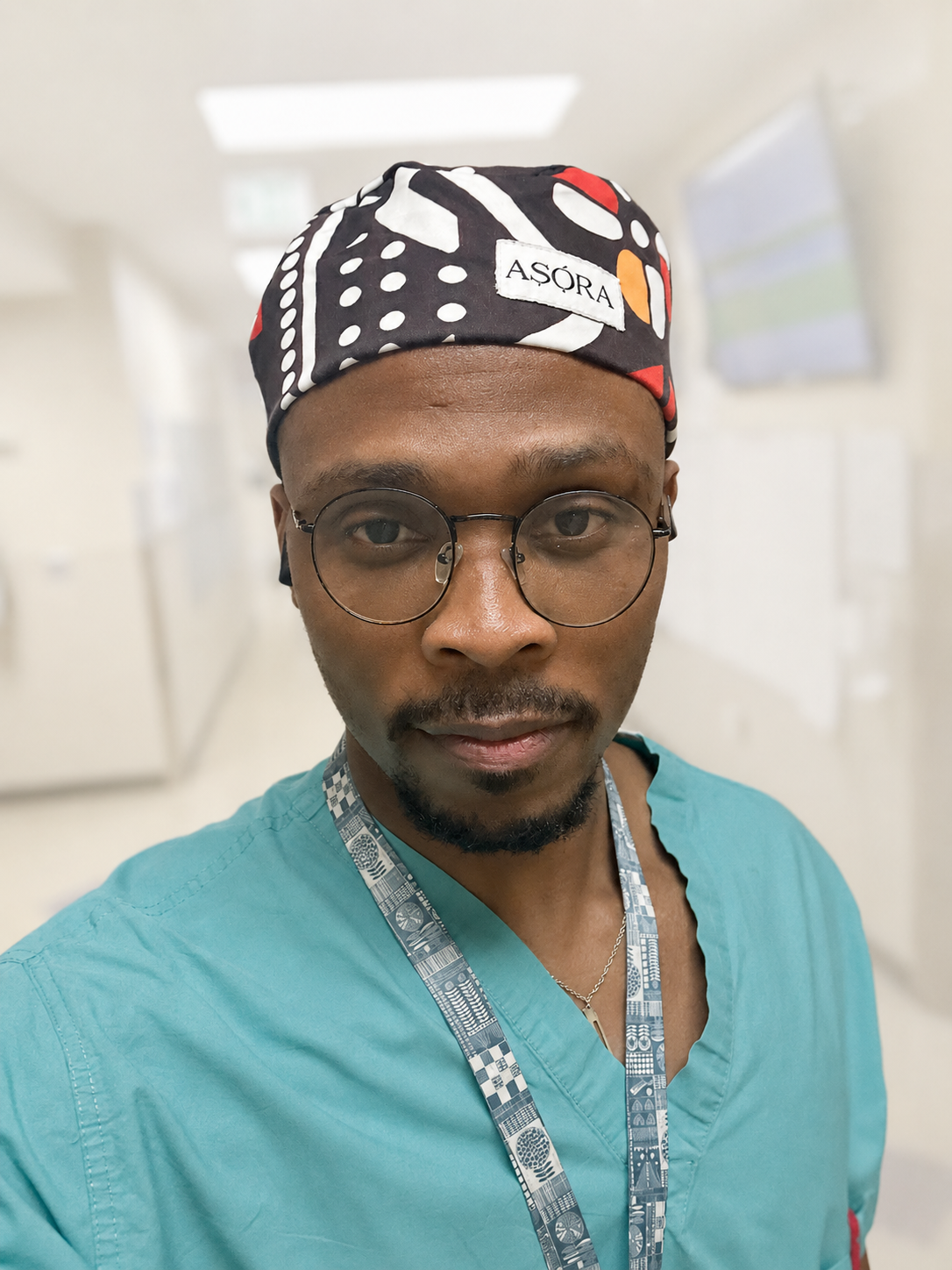 Person wearing a colorful  ASORA Imole scrub cap and teal scrubs in a medical setting
