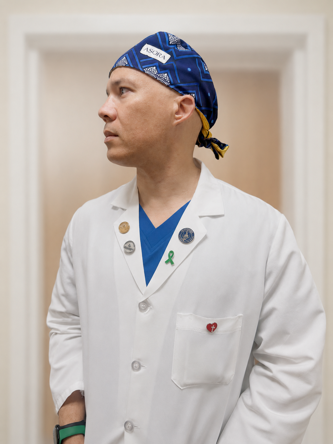 Person wearing a white lab coat with a blue ASORA Scrub cap and a visible brand logo.