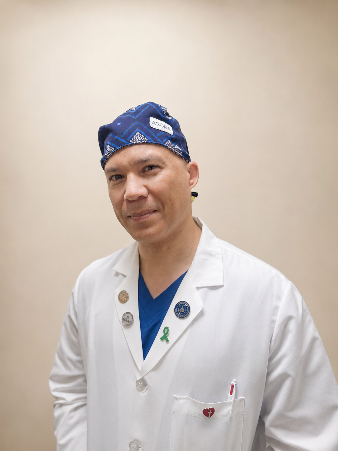 Doctor wearing a white coat and blue ASORA Akin scrub cap with a beige background