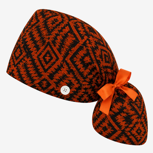 Orange and black patterned ASORA ponytail scrub cao with a button and orange ribbon on a white background